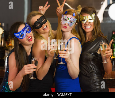 Attraktive Frauen tragen Masken mit Champagner Stockfoto