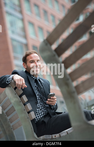 Business-Leute. Ein Mann in einem Anzug, auf einer Bank sitzen. Stockfoto