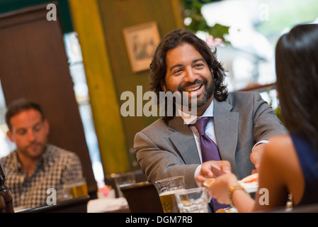 Business-Leute. Zwei Menschen sitzen an einem Tisch, Hand in Hand. Ein Mann im Hintergrund. Stockfoto