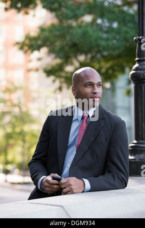 Business-Leute. Ein Mann in einem Anzug, stützte sich auf eine Balustrade unter einem Laternenmast. Warten. Stockfoto