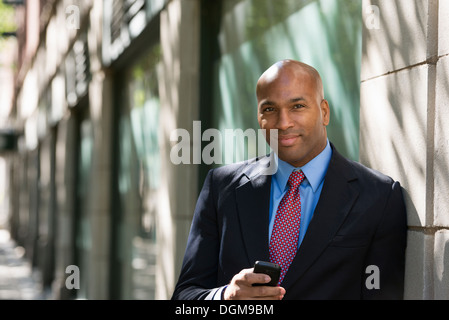 Business-Leute. Ein Geschäftsmann in Anzug und Krawatte rot, sein Telefon zu überprüfen. Stockfoto