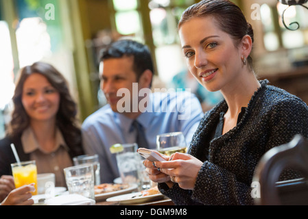 Business-Leute. Drei Personen an einem Cafétisch, eine Frau drehte sich um, hielt eine Glas Weine. Stockfoto