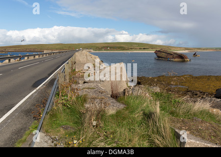 Inseln von Orkney, Schottland. A961 bei Churchill Barrier Nummer 3 mit einer versunkenen Blockship im Hintergrund. Stockfoto