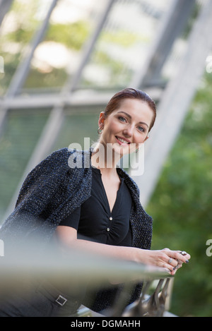 Business-Leute. Eine Frau in eine graue Jacke mit ihrem Haar, stützte sich auf ein Geländer. Stockfoto