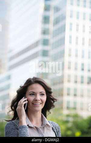 Business-Leute. Eine Geschäftsfrau in eine leichte graue Jacke mit ihrem Smartphone. Stockfoto