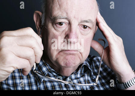 Nachdenklich Senior seine Brille in der Hand hält Stockfoto