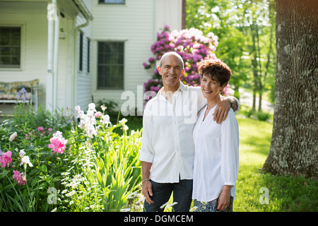 Bio-Bauernhof. Sommer-Party. Ein älteres Paar in weißen Hemden, die unter den Blumen zusammenstehen. Stockfoto