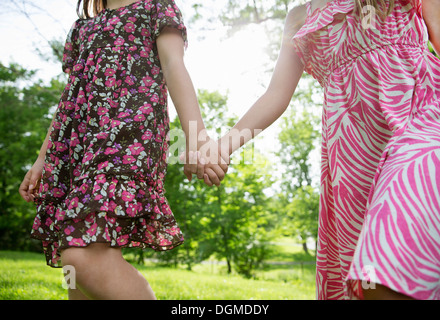 Ein Sommer-Familientreffen auf einem Bauernhof. Zwei Kinder Hand in Hand und quer über den Rasen. Stockfoto