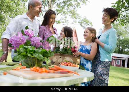 Familienfest. Ein Tisch gedeckt mit Salaten und frischem Obst und Gemüse. Eltern und Kinder. Stockfoto