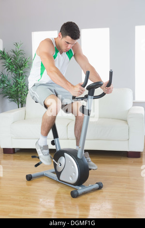 Sportlich gut aussehender Mann training am Heimtrainer Stockfoto