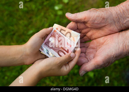 Kind, Geld an eine ältere Frau Stockfoto