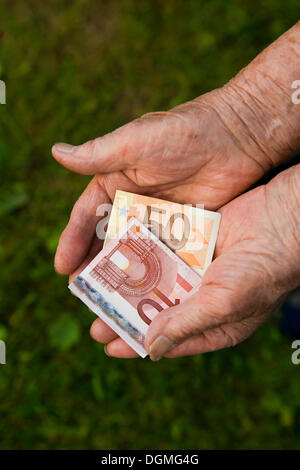 Ältere Frau, die Euro-Banknoten in ihren Händen hält Stockfoto