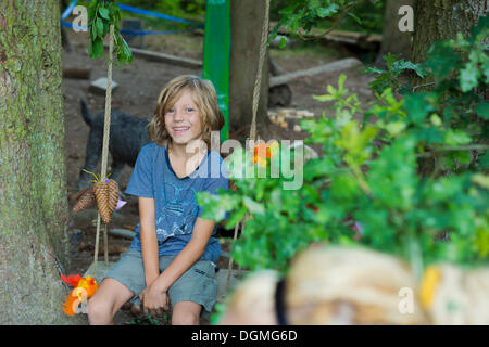 Junge sitzt auf einer Schaukel im Waldkindergarten, Ilmmuenster, Bayern Stockfoto