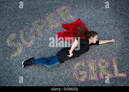 Junge Frau erscheint in einem Superman oder Supergirl Standpunkt, Text "Super Girl" von oben fliegen Stockfoto