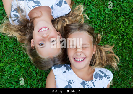 Zwillingsmädchen, 9, auf der Wiese liegend Stockfoto