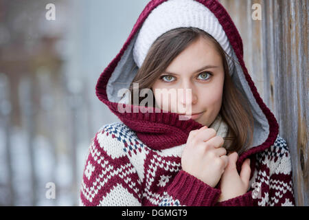 Junge Frau trägt einen gestrickten Pullover mit Kapuze, Porträt, Deutschland Stockfoto