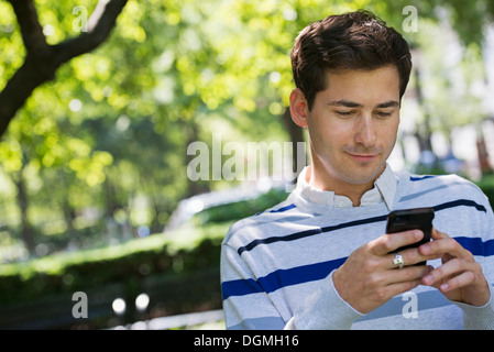 Sommer. Business-Leute. Ein Mann, sein Smartphone für Nachrichten überprüfen. Stockfoto