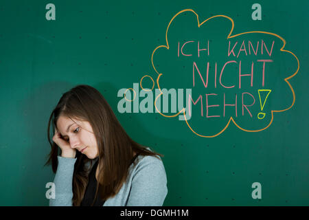 Deprimiert aussehende Lehrer steht vor der Tafel mit einer Sprechblase, "Ich Kann Nicht Mehr", Deutsch für "Ich kann nicht Stockfoto