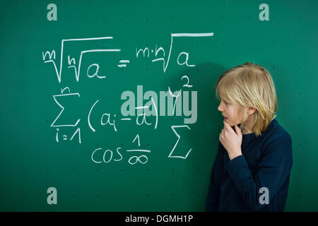 Schuljunge Grübeln eine mathematische Formel auf eine Schultafel, Deutschland Stockfoto