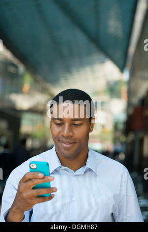 Geschäftsleute unterwegs. Ein Mann in einem offenen necked Hemd überprüft sein Telefon. Stockfoto