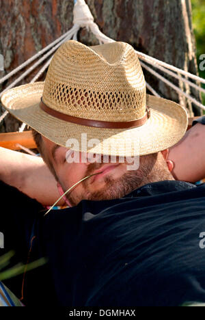 Schlafen in einer Hängematte mit einem Hut übers Gesicht Mann Stockfoto