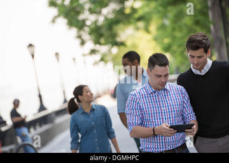 Sommer in der Stadt. Vier Personen in einer Gruppe. Ein mit seiner digital-Tablette. Stockfoto