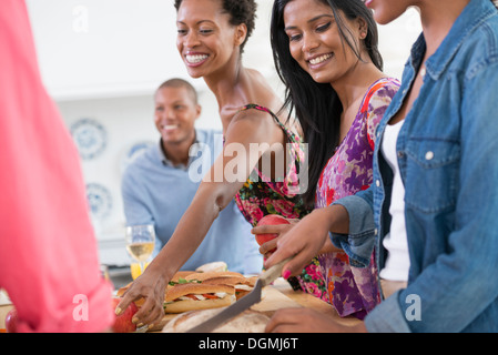 Ein informelles Büro-Ereignis. Menschen, die Ausgabe von Platten von Lebensmitteln über ein Buffet-Tisch. Stockfoto