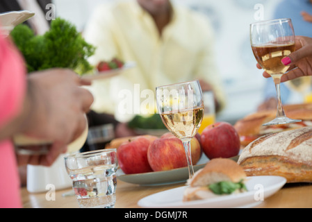 Ein informelles Büro-Ereignis. Menschen, die Ausgabe von Platten von Lebensmitteln über ein Buffet-Tisch. Stockfoto