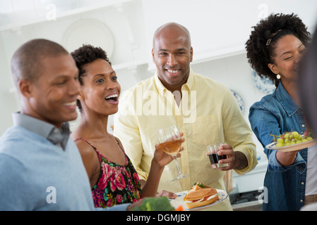 Eine informelle Betriebsfest. Menschen, die Ausgabe von Platten von Lebensmitteln über ein Buffet-Tisch. Stockfoto