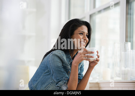 Eine junge Frau trägt ein Jeanshemd holding eine China-Schale. Stockfoto