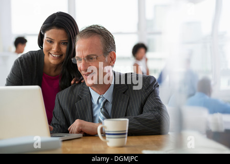 Büro. Zwei Menschen, ein Mann und eine Frau, einen Laptopcomputer teilen. Stockfoto