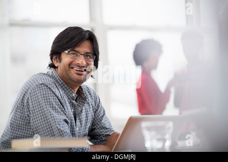 Büroalltag. Ein junger Mann sitzt an einem Schreibtisch mit einem Laptop.
