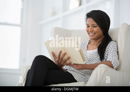 Büroalltag. Eine Frau auf einem Sofa sitzt mit einem digitalen Tablet. Stockfoto