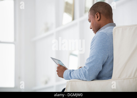 Büroalltag. Ein Mann sitzt mit einem digitalen Tablet. Stockfoto