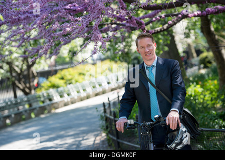 Ein Mann im Anzug, mit dem Fahrrad, mit einem Fahrradhelm in seinen Händen. Stockfoto