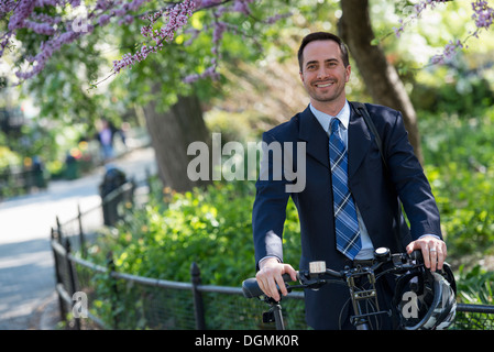 Ein Mann in einem Geschäft passen rittlings auf einem Fahrrad mit Helm in der hand. Stockfoto