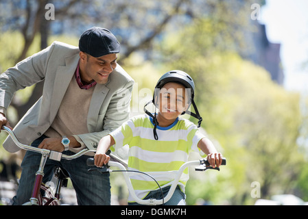 Eine Familie im Park an einem sonnigen Tag. Vater und Sohn, Radfahren Stockfoto