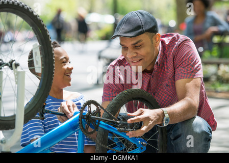 Eine Familie im Park an einem sonnigen Tag. Vater und Sohn ein Fahrrad reparieren. Stockfoto