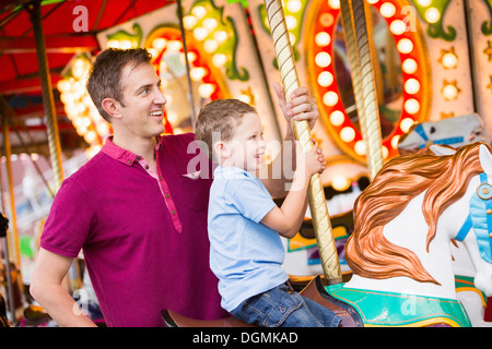 USA, Utah, Salt Lake City, Vater und Sohn (4-5) auf Karussell im Vergnügungspark Stockfoto