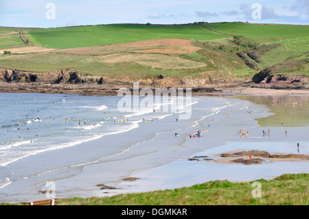 North Cornwall - Polzeath Felsenweg - Blick über den Strand und sanft brechenden Wellen zu Pentireglaze - weiß braun und grün Stockfoto