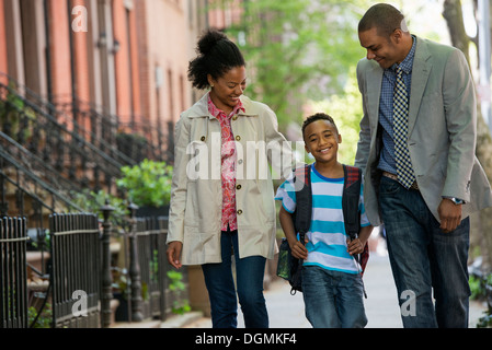 Eine Familie im Freien in der Stadt. Zwei Eltern und ein kleiner Junge zusammen spazieren. Stockfoto