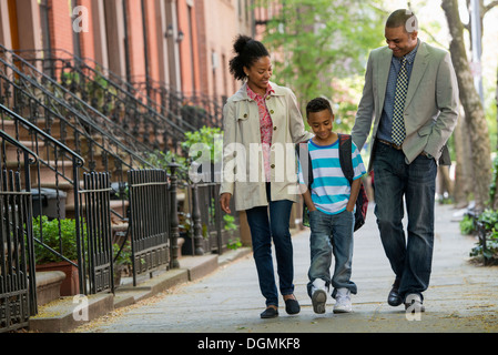 Eine Familie im Freien in der Stadt. Zwei Eltern und ein kleiner Junge zusammen spazieren. Stockfoto