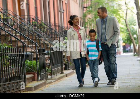 Eine Familie im Freien in der Stadt. Zwei Eltern und ein kleiner Junge zusammen spazieren. Stockfoto