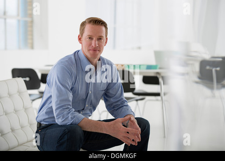 Geschäft. Ein Mann in einem blauen Hemd sitzen. Stockfoto