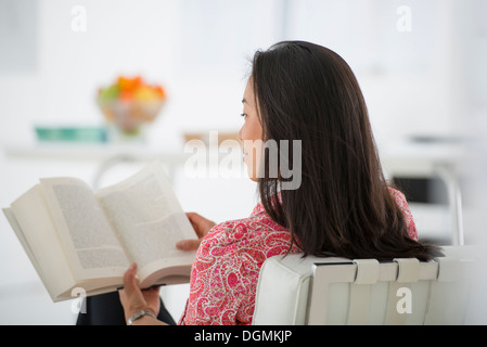 Geschäft. Eine Frau sitzt und liest ein Buch. Forschung oder Entspannung. Stockfoto
