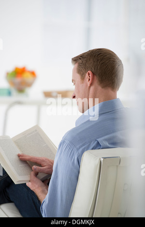 Geschäft. Ein Mann sitzt, der ein Buch in seinen Händen hält. Lesen. Im Mittelpunkt der Seite. Hinten Sie Ansicht von. Stockfoto