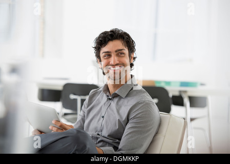 Geschäft. Ein Mann sitzt lächelnd und halten eine digitale-Tablette. Stockfoto