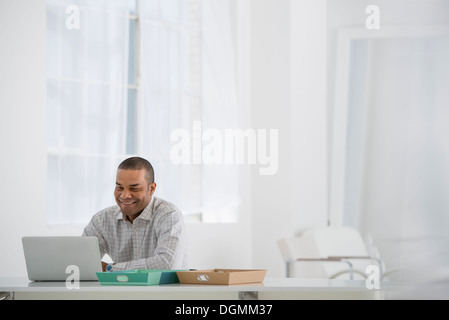 Geschäft. Ein Mann sitzt an einem Schreibtisch mit einem Laptop. Stockfoto
