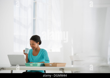 Arbeitsumfeld, hell und luftig. Eine Frau sitzt mit einem Laptop. Stockfoto