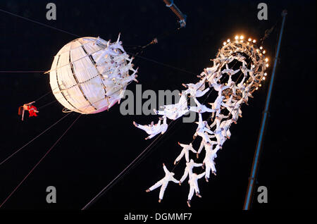 Weiß gekleidete Trapezkünstler und Globus schweben in den Himmel, globale Rheingold, Open-Air-Theater von La Fura Dels Baus Stockfoto